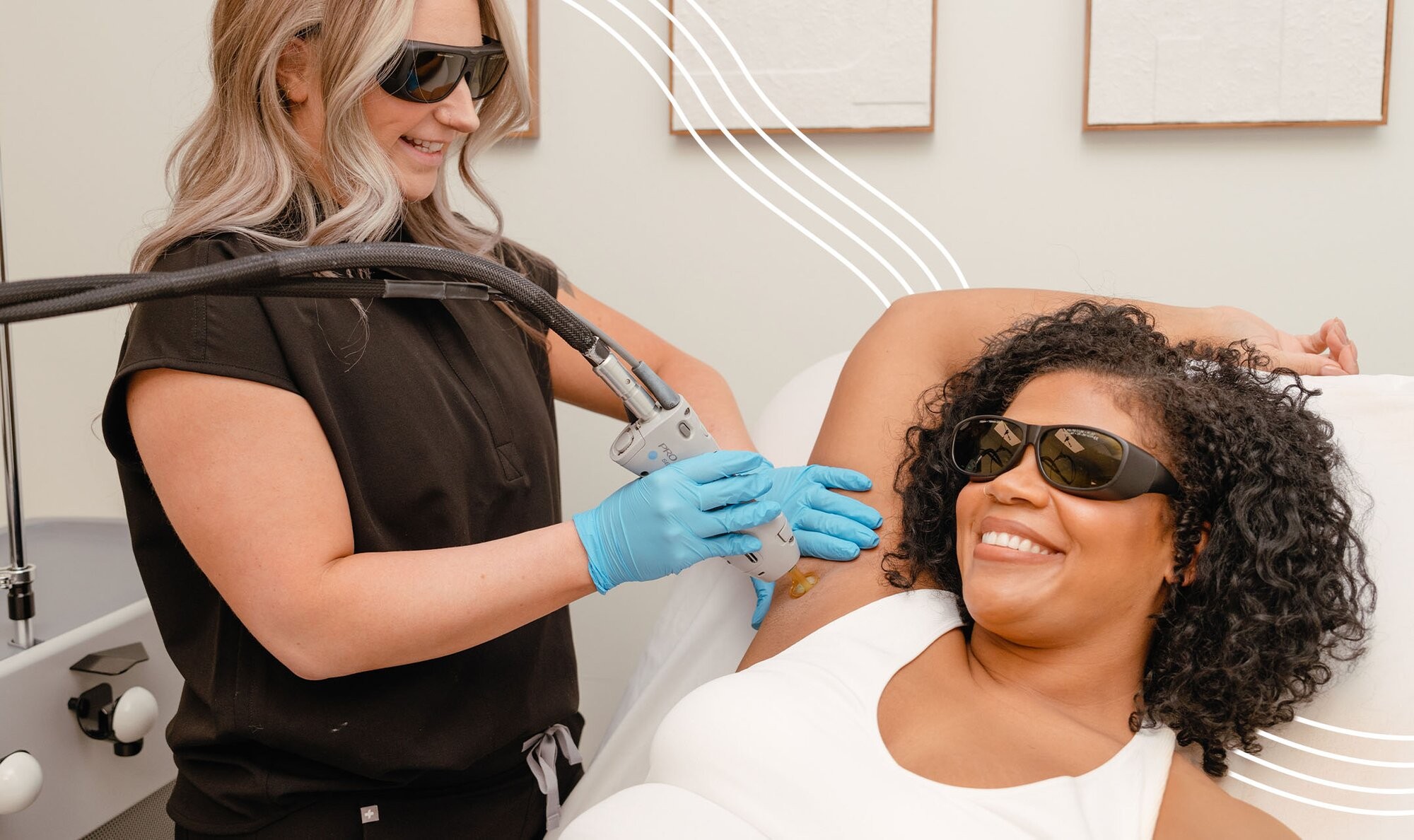 Woman with black curly hair raising her arm above her head and smiling while getting laser hair removal as a hero image for a page on the Milan Difference