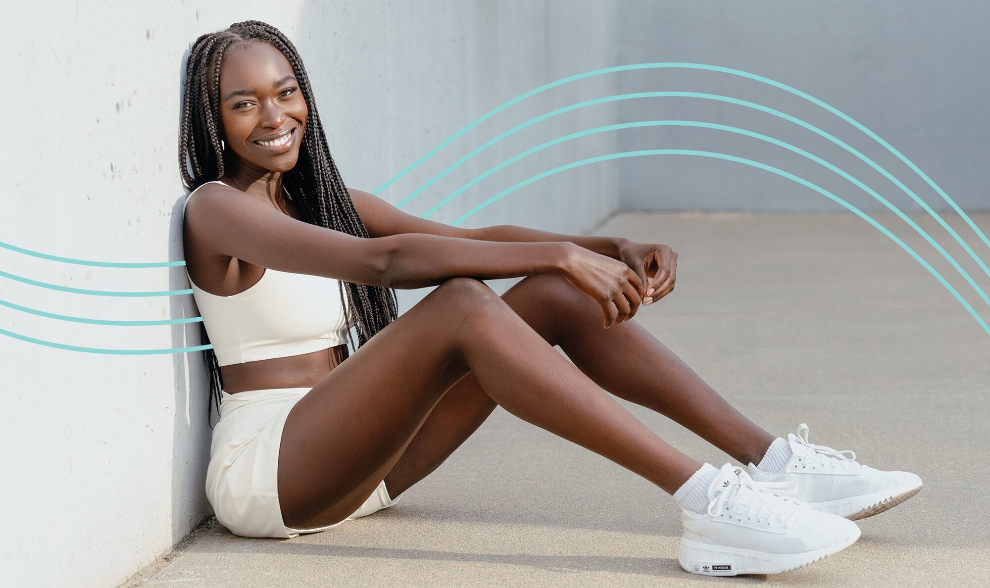 Confident woman sitting on the ground with her legs up smiling with newfound confidence because she got buttocks laser hair removal